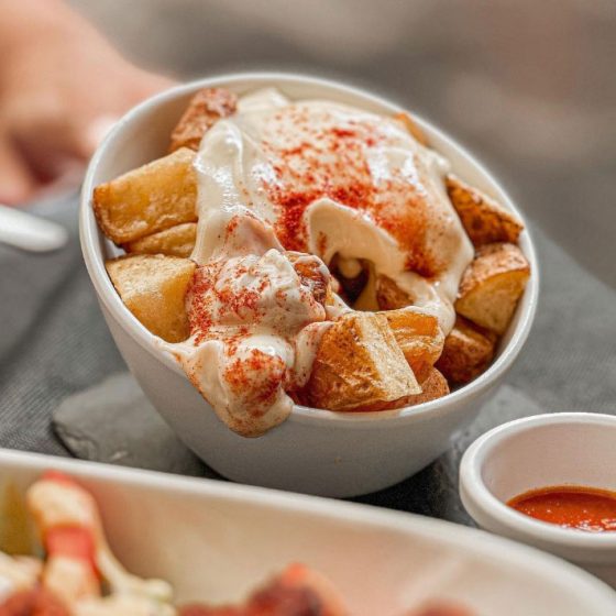 Patatas bravas tradicionales del Bar El León en Valencia, con salsa picante y alioli