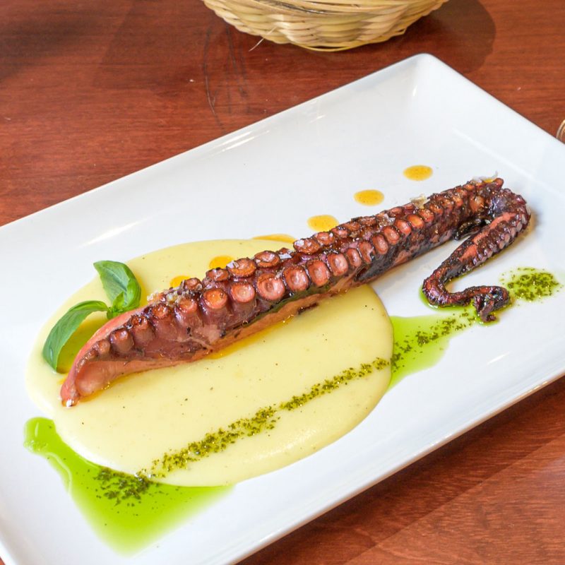 Pulpo a la plancha sobre parmentier acompañado de aceite de albahaca y aceite de pimentón.
